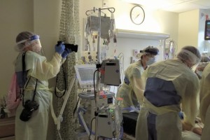 Erin Schaff photographing a covid patient receiving treatment in a hospital.