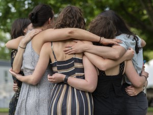 Five alumni with their backs to us hugging at reunion