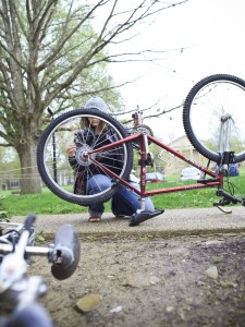 A student fixing the back wheel of a bicycle