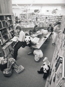 An archival photo of the bookstore with people reading at a table and browsing the shelves