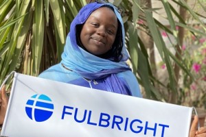 Recent Kenyon Fulbright scholar holding a Fulbright banner